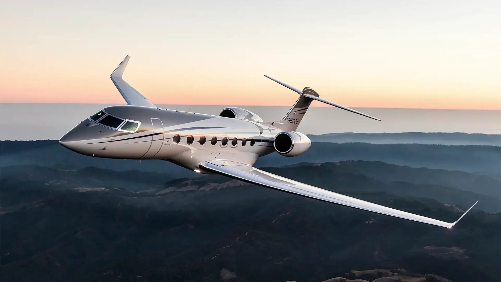 A private jet in flight above the mountains at dusk