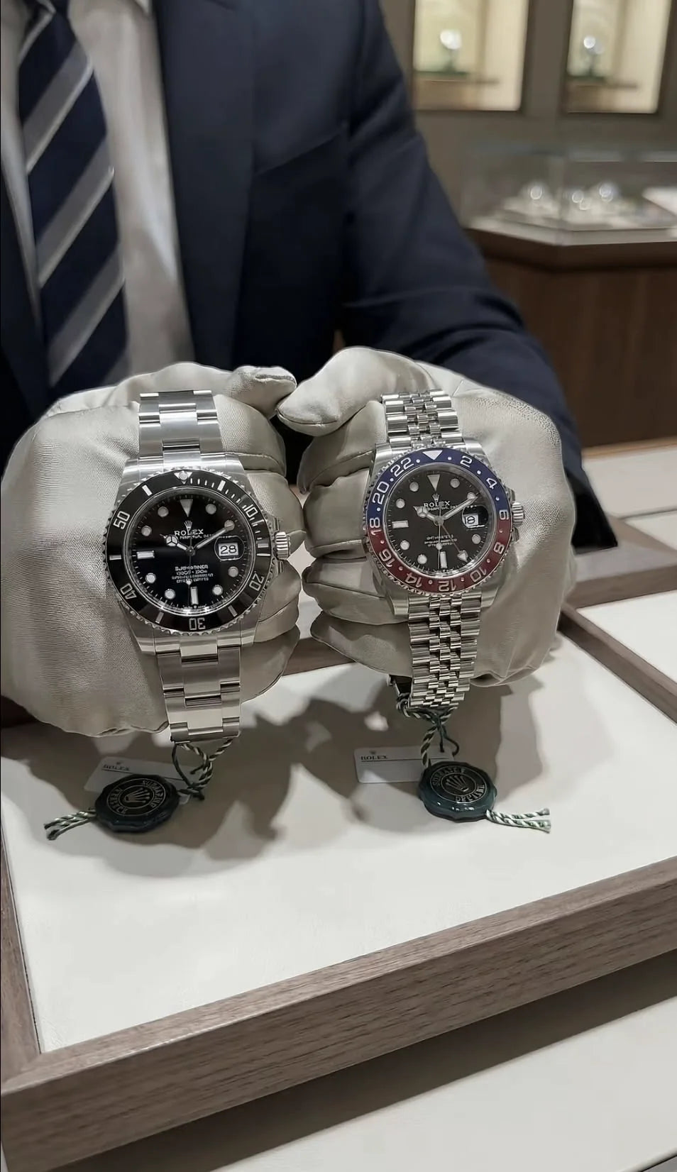 Two watches presented with white gloves
